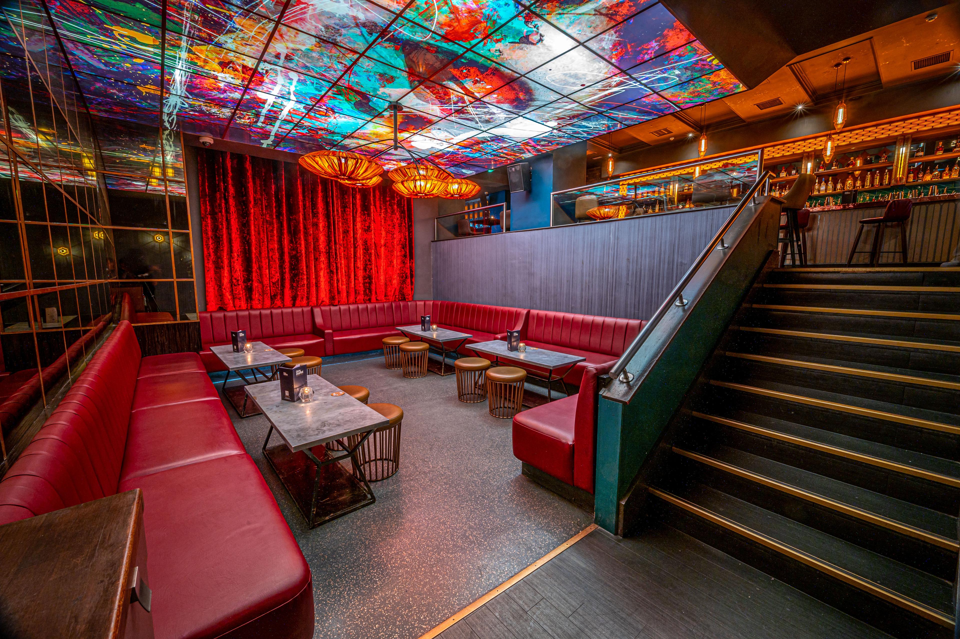 A private hire space seating area with red booth seating and an artwork ceiling