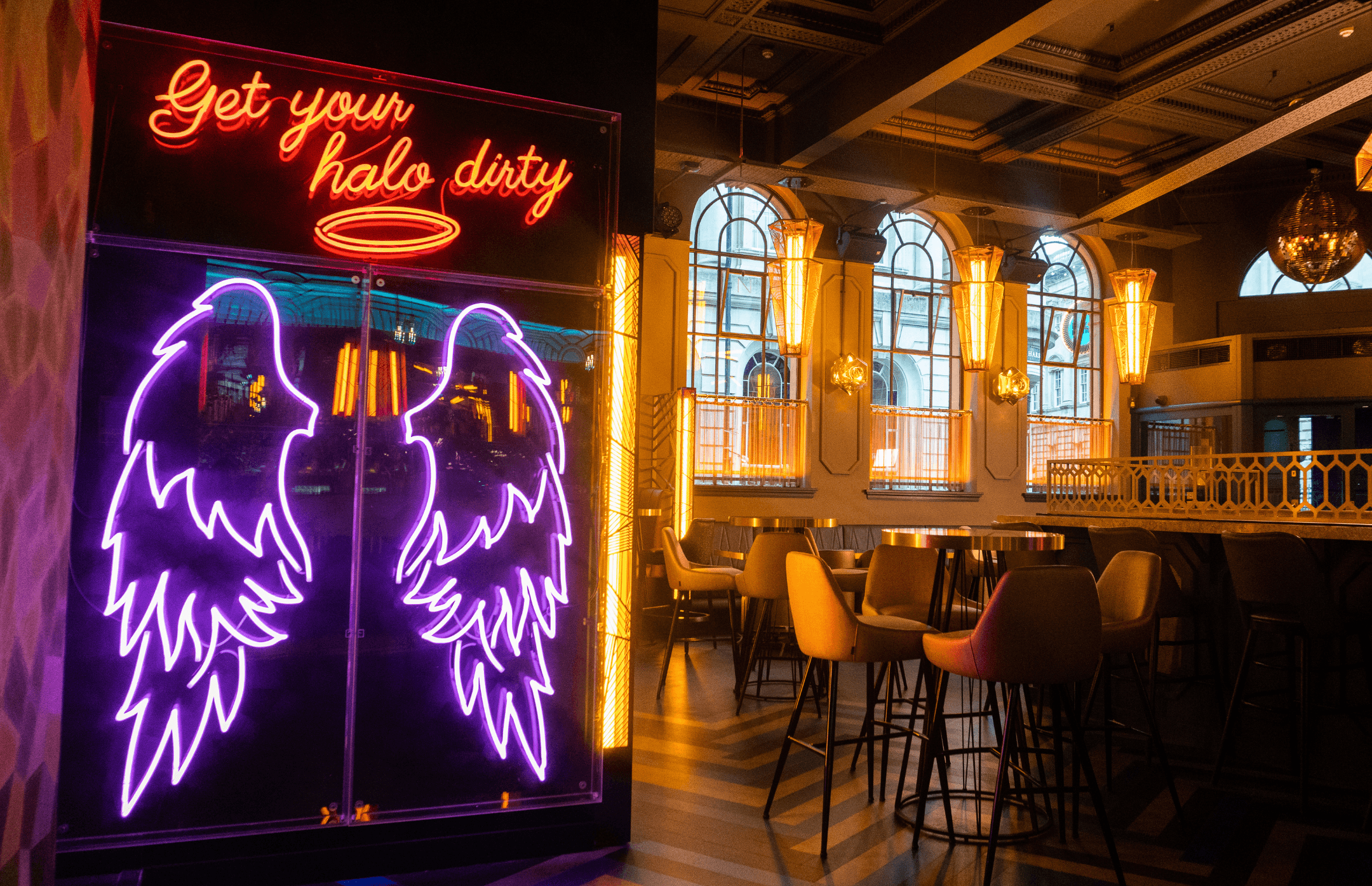 Neon angel wings sign and seating area in Dirty Martini Bristol